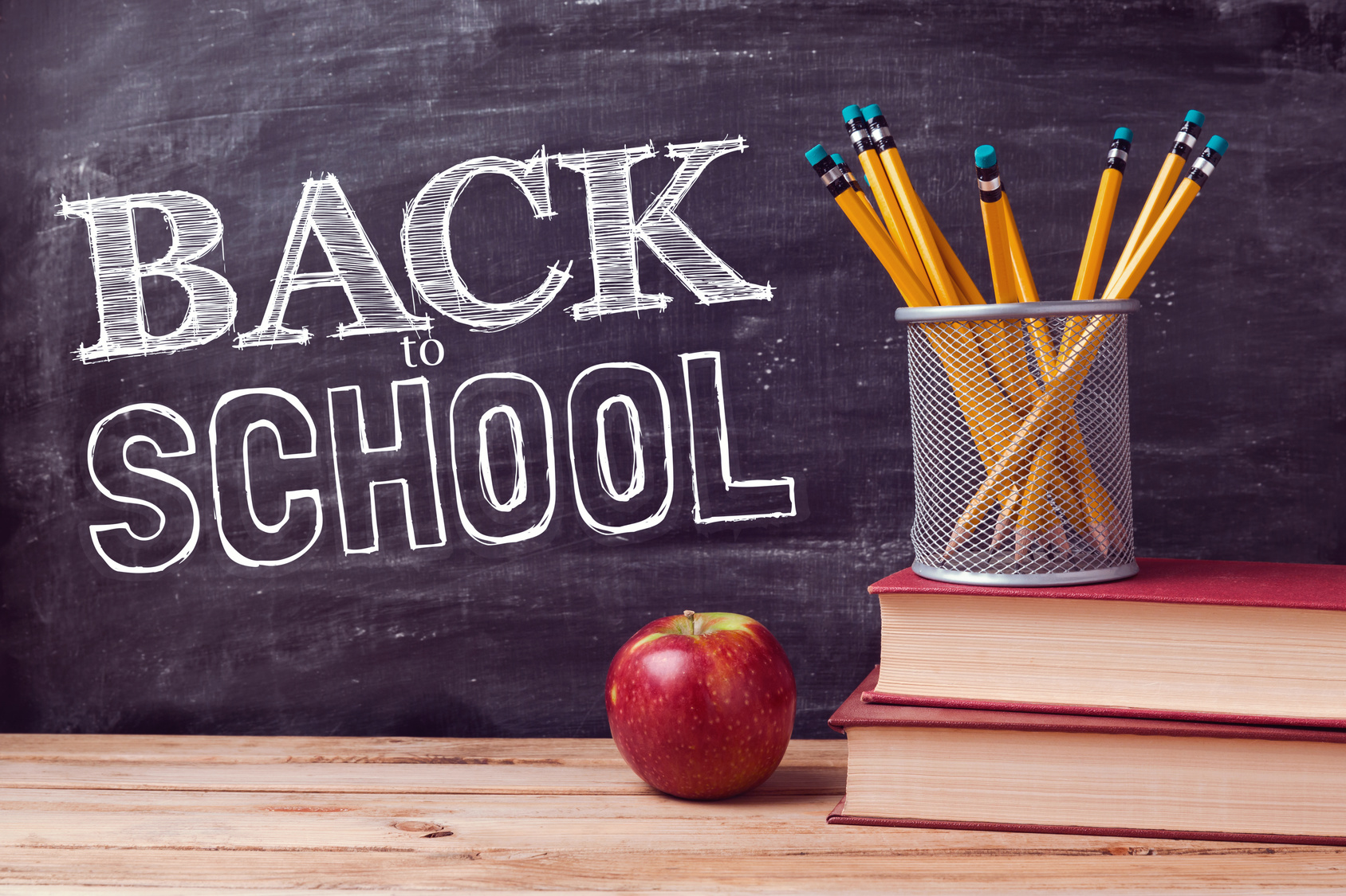 Back to school lettering with books, pencils and apple over chalkboard